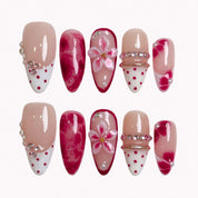 Ruby Petal Reverie press-on nails in red, pink, nude, and white with 3D flowers, crystals, polka dots, and marble details