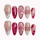 Ruby Petal Reverie press-on nails in red, pink, nude, and white with 3D flowers, crystals, polka dots, and marble details