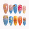 Tropical Shell Bloom press-on nails in nude, blue, orange, yellow, and gold with flowers, shells, starfish, pearls, and 3D details